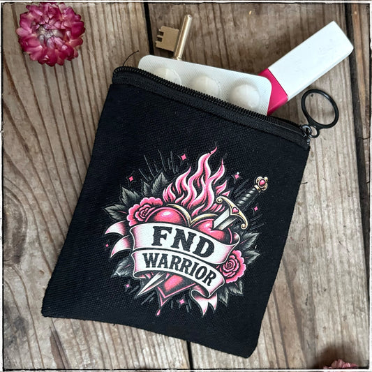 A black canvas zippered pouch with a colorful tattoo-style graphic reading 'FND WARRIOR' on the front, shown on a rustic wooden surface with a key, pill bottle, and small flower prop.